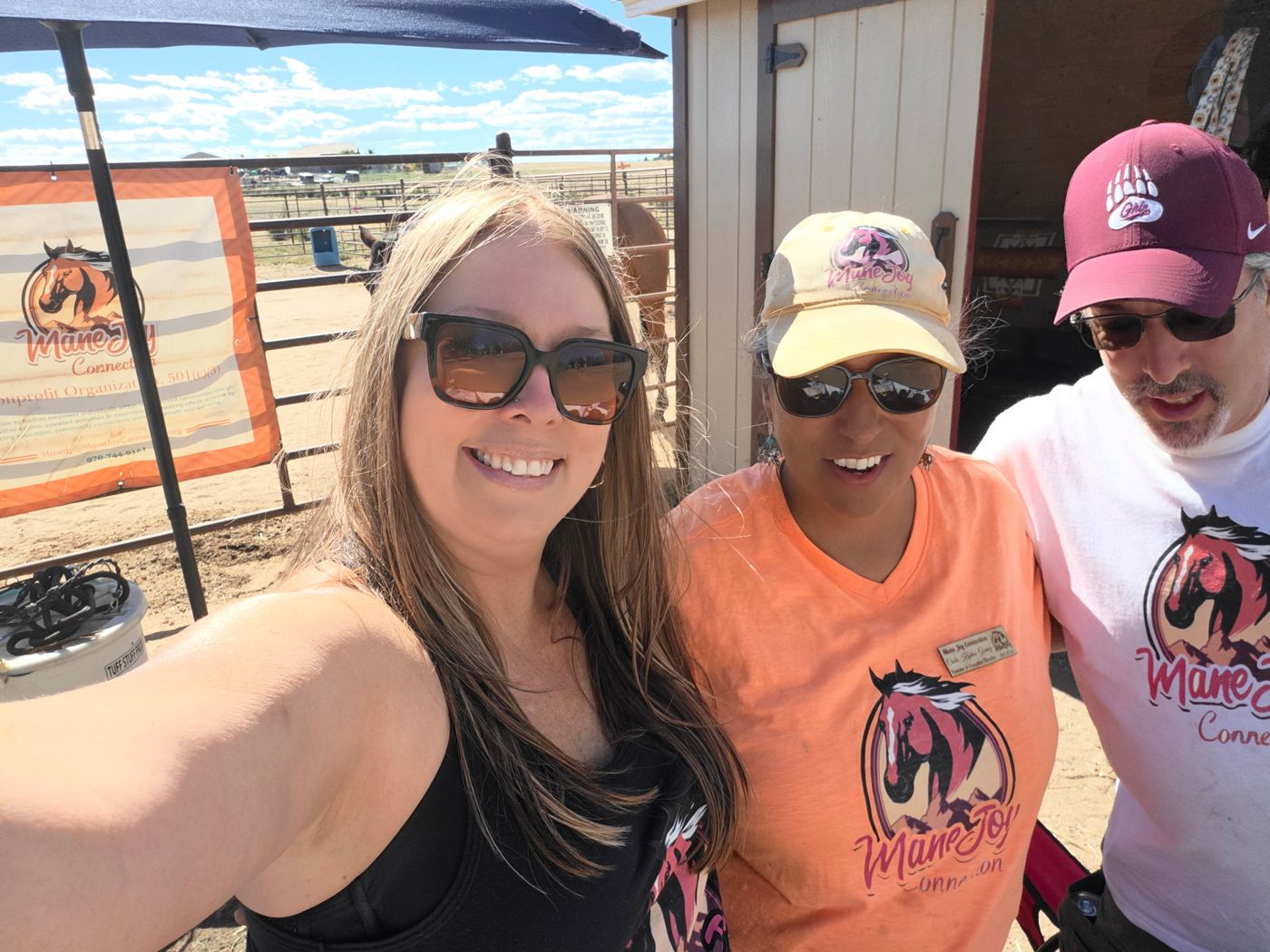 Carla and two supporters in Mane Joy shirts smiling at the 2026 SonFlower Ranch Shindig booth