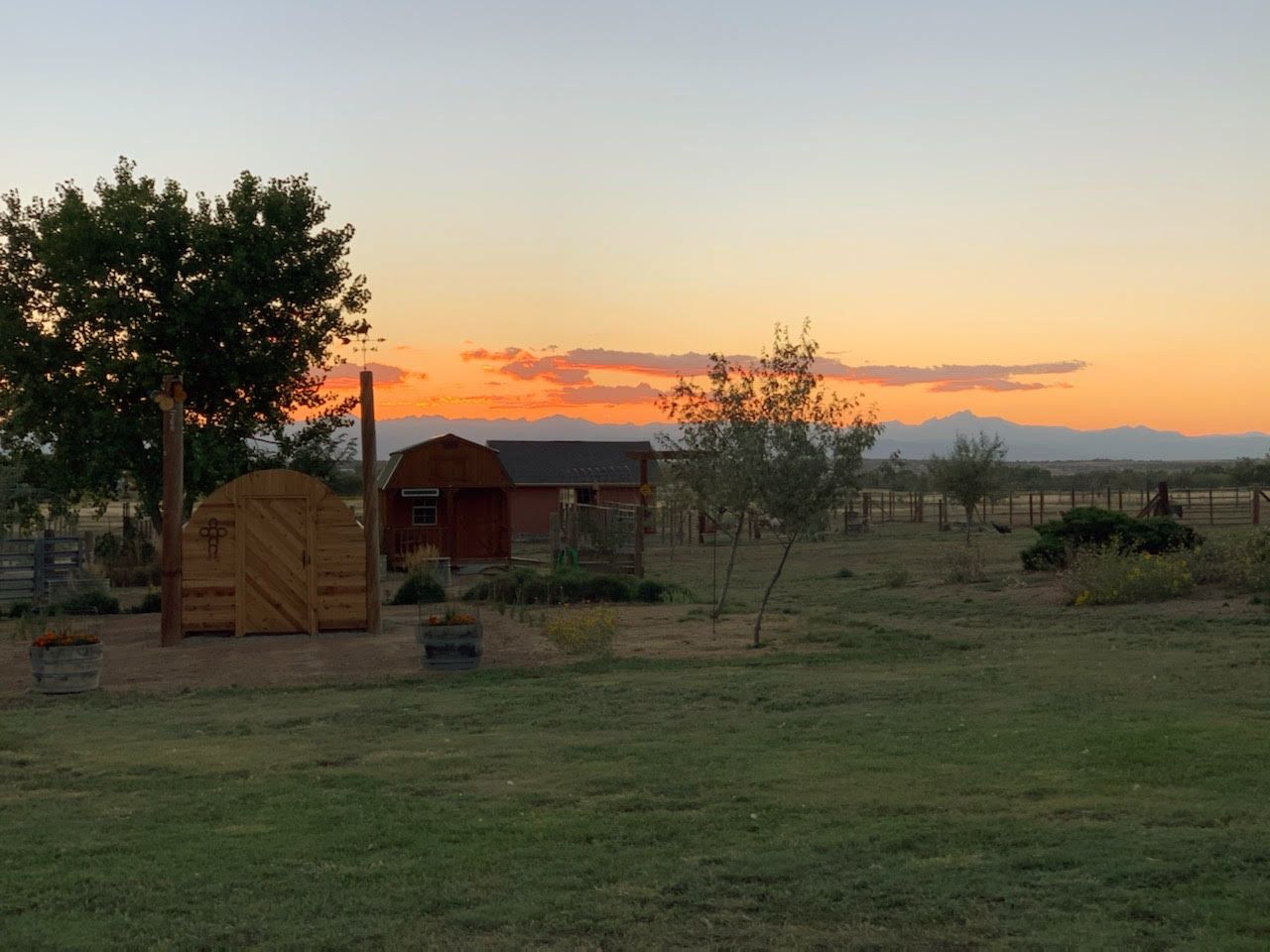Sunset glowing orange over the barns and pasture at SonFlower Ranch